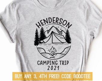 Może przedstawiać: Szary T-shirt z czarno-białym nadrukiem przedstawiającym scenę górską z namiotem, ogniskiem i tekstem "Henderson Camping Trip 2021". Na koszulce znajduje się również tekst "Buy any 3, 4th free! Code Boootee".