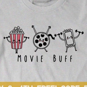 Może przedstawiać: Szary T-shirt z grafiką wiaderka popcornu, rolki filmowej i biletu do kina, wszystkie trzymające ciężarki. Tekst "MOVIE BUFF" znajduje się pod grafiką. Tekst "BUY ANY 3, 4TH FREE! CODE BOOTEE" znajduje się pod grafiką.