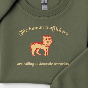 May include: A white ceramic mug with a black handle and the text "But First, Coffee" in a bold, black font. The mug is set against a blurred background, suggesting a cozy setting.