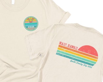 May include: Two beige t-shirts with a retro sunset graphic on the back of one shirt. The back of the shirt says "MAUI! HAWAII" and "Smith Family Trip 2023". The front of the other shirt has a small graphic of a sunset with the year "2013" underneath.