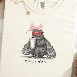 Camiseta divertida de Mothma'am con colores cómodos y temática de Mothman. Camiseta de fantasía sobrenatural con temática de criptidos, criptidos y Mothman.