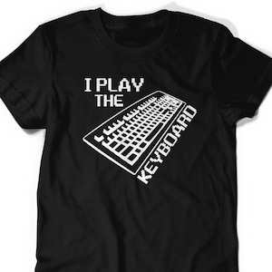 May include: Black t-shirt featuring the white text "I PLAY THE KEYBOARD" and a white keyboard graphic. The top has short sleeves and a crew neck.