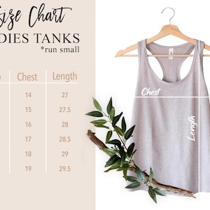 May include: A light grey ladies' tank top on a wooden hanger, with a size chart to the left. The size chart includes chest and length measurements. The text "Size Chart LADIES TANKS *run small" is at the top.