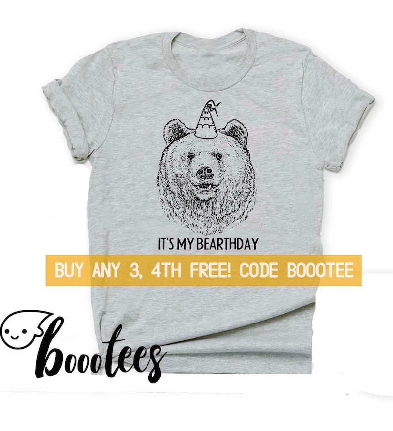 K&ouml;nnte beinhalten: Graues T-Shirt mit einer schwarz-wei&szlig;en Illustration eines B&auml;ren, der einen Partyhut tr&auml;gt. Der Text "It's my Bearthday" ist unter dem B&auml;ren gedruckt. Der Text "Buy any 3, 4th free! Code Bootee" ist unter dem Text gedruckt.
