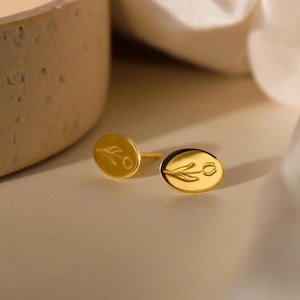 Könnte beinhalten: Ein Paar goldene, ovale Ohrringe mit einem zarten Tulpenmotiv.