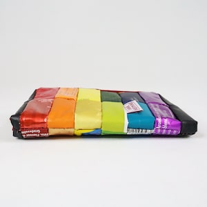 May include: A rainbow-coloured pouch made from recycled sweet wrappers. The pouch is made of different coloured wrappers, including red, orange, yellow, green, blue, and purple. The pouch has a black leather flap on the top.