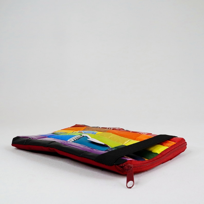 May include: A rainbow-coloured zippered pouch made from recycled materials. The pouch has a black strap and a red zipper pull.