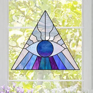May include: A stained glass window featuring a blue eye inside a triangle with purple and blue stripes radiating from the eye.