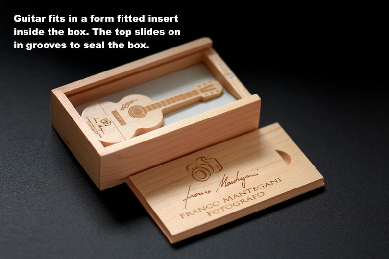 K&ouml;nnte beinhalten: Eine Holzkiste mit einem Schiebedeckel, die einen h&ouml;lzernen USB-Stick in Form einer Gitarre enth&auml;lt. Die Kiste ist mit dem Text "froms Martyni FRANCO MANTEGANI FOTOGRAFO" graviert.