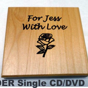May include: A wooden CD/DVD case with the words "For Jess With Love" and a rose illustration engraved on the top. The case is made of alder wood and has a natural wood grain finish. The text "ALDER Single CD/DVD case" is at the bottom.