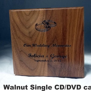 May include: A walnut CD/DVD case with engraved wedding rings and the text "Our Wedding Memories," along with the names Felicia & George and the date September 5, 2015. The case is rectangular and made of wood.