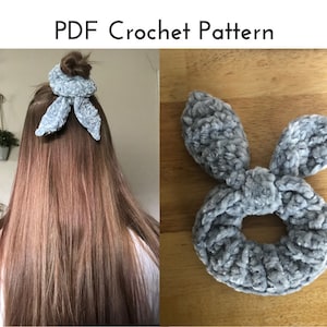 May include: A gray, plush scrunchie with bunny ear accents. The scrunchie is shown in a person's hair and also lying flat on a wooden surface. The text "PDF Crochet Pattern" is at the top of the image.