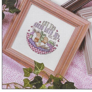 Könnte beinhalten: Ein Set aus drei Keramikbechern mit einer gesprenkelten, cremefarbenen Glasur. Jeder Becher hat ein anderes handgemaltes Design: ein blaues und grünes Blatt, eine gelbe Blume und eine rote Beere. Die Becher haben eine einfache, abgerundete Form.