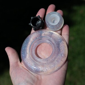 May include: A set of three resin components including a large, translucent, circular ring with iridescent glitter, a smaller translucent circular piece with glitter, and a small, black, textured, multi-pointed star-shaped object.