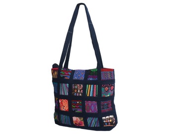 May include: A blue tote bag with a patchwork design of colourful squares. The squares feature geometric and floral patterns in shades of red, pink, green, blue, and yellow.