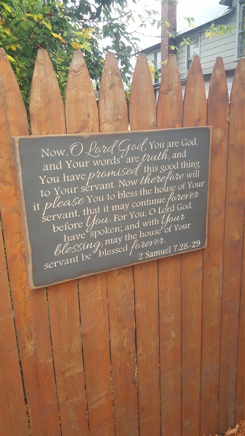 May include: A wooden sign with a gray background and white text. The sign features a bible verse from 2 Samuel 7:28-29, which reads: "Now, O Lord God, You are God, and Your words are truth, and You have promised this good thing to Your servant. Now therefore will it please You to bless the house of Your servant, that it may continue forever before You. For You, O Lord God, have spoken; and with Your blessing, may the house of Your servant be blessed forever. 2 Samuel 7:28-29"