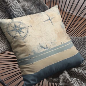 May include: A decorative throw pillow with a nautical theme. The pillow features a compass, anchor, and stripes in shades of blue and beige.