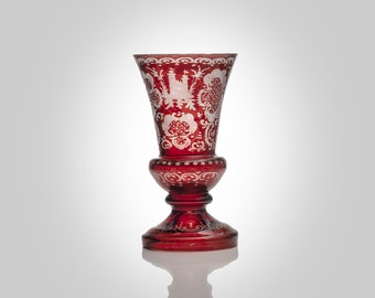 May include: A red glass vase with a white etched design. The vase has a wide mouth and a narrow base.