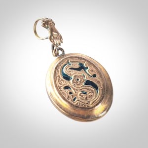 May include: Gold locket with an ornate design featuring a blue enamel letter 'S' surrounded by floral motifs.