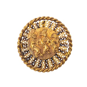 May include: A vintage gold-toned brooch with a detailed design. The brooch features a central circular medallion with figures in relief, surrounded by an openwork filigree and a twisted rope border. The overall design is ornate and detailed.