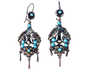 May include: A pair of antique earrings with a dark metal finish, adorned with turquoise-colored stones and intricate leaf and floral designs. Each earring features a small, dangling teardrop-shaped charm at the bottom, creating an elegant and vintage aesthetic.