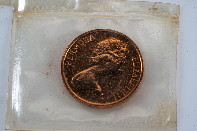 Pu&ograve; includere: Una moneta di colore rame con le parole "BERMUDA" e "ELIZABETH II" incise attorno al bordo. La moneta presenta un profilo della regina Elisabetta II.
