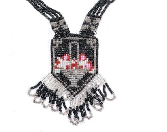 May include: A black beaded necklace with a pendant featuring a geometric design with red, pink, and white accents. The pendant has a fringe of black and silver beads.