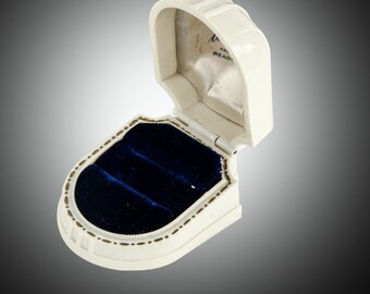 May include: White ring box with a blue velvet interior. The box is open and the lid is tilted back. The lid has the text "48 READ"