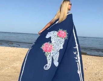 May include: A large navy blue rectangular beach towel featuring a white leopard silhouette adorned with two vibrant pink floral clusters. The towel is framed by a white bamboo-style border and finished with decorative fringe along the bottom edge.