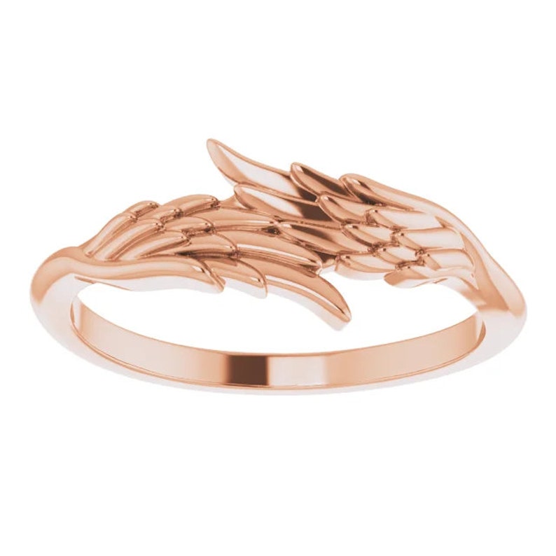 May include: A rose gold ring featuring a detailed angel wing design. The wings are delicate and intricate, with a smooth finish.