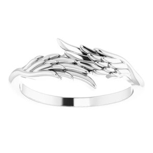 May include: Silver ring featuring a detailed angel wing design. The wing is curved and wraps around the finger.