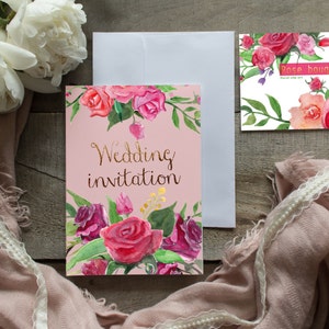 Puede incluir: Una tarjeta de invitaci&oacute;n de boda rosa con un dise&ntilde;o floral y las palabras "Wedding invitation" en letras doradas. La tarjeta est&aacute; adornada con rosas de acuarela en tonos rosa y rojo. Tambi&eacute;n hay un sobre blanco y una tarjeta "Rose bouquet".