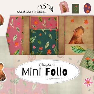 Puede incluir: Una ilustración en acuarela de un mini folio con temática de carpincho. El folio presenta un diseño floral rosa y verde, con pegatinas y etiquetas adicionales de carpincho. El texto "Capybara Mini Folio" se muestra en un óvalo blanco.