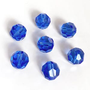 May include: Seven cobalt blue faceted glass beads, each with a round shape and a slightly different angle.