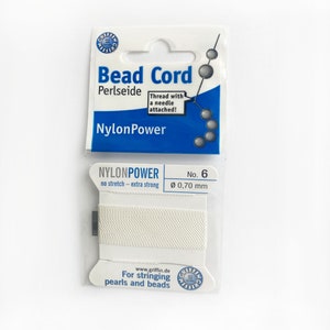 May include: White bead cord with a needle attached, labelled "Bead Cord Perlseide NylonPower" and "NYLONPOWER no stretch - extra strong No. 6 Ø 0,70 mm". The packaging also says "For stringing pearls and beads" and "www.griffin.de".