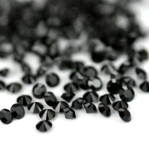Puede incluir: Una dispersi&oacute;n de diamantes de imitaci&oacute;n de cristal negro sobre una superficie blanca.