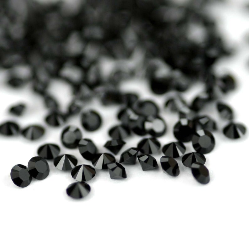 Puede incluir: Una dispersi&oacute;n de diamantes de imitaci&oacute;n de cristal negro sobre una superficie blanca.