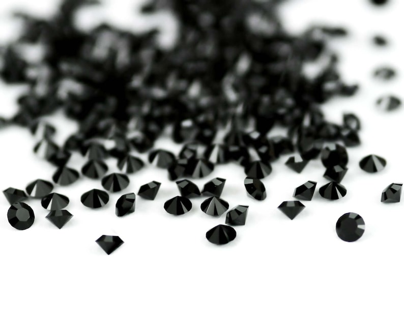 Puede incluir: Una dispersi&oacute;n de diamantes de imitaci&oacute;n negros en forma de diamante sobre un fondo blanco.