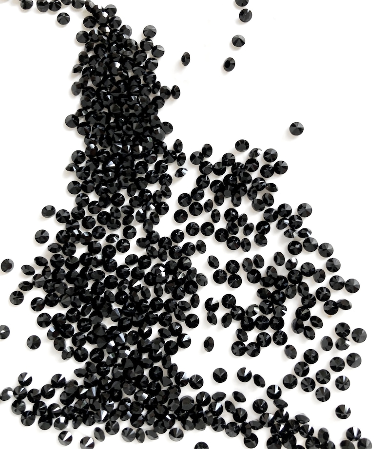 Puede incluir: Una dispersi&oacute;n de cristales negros en forma de diamante sobre un fondo blanco.