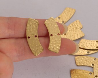 May include: A collection of gold-coloured, curved metal jewellery components with a hammered texture. Each piece has two small holes for attachment. The components are arranged on a light background, suggesting a craft or jewellery-making theme.