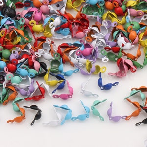 Könnte beinhalten: Eine große Auswahl an bunten Metallkappen mit einer kleinen Schlaufe oben. Die Kappen sind in verschiedenen Formen und Größen, darunter rund, quadratisch und dreieckig.