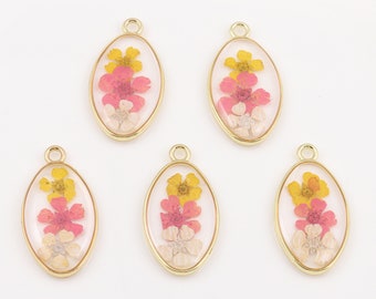 May include: Five gold oval-shaped charms with a clear resin insert containing pressed pink, white, and yellow flowers.