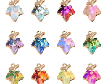 May include: Twelve gold leaf charms shaped like a leaf with a crystal in the center. The crystals are in various colors including pink, purple, blue, green, orange, and clear.