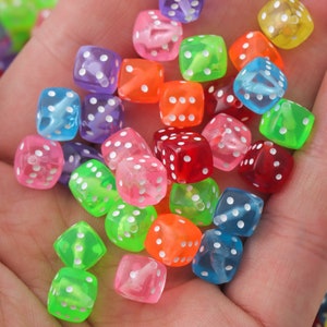 Puede incluir: Una colección de dados translúcidos de colores con puntos blancos. Los dados son de plástico y de varios colores, incluyendo rojo, azul, verde, amarillo y rosa.
