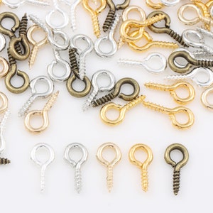 Puede incluir: Surtido de ganchos de ojal con tornillo en acabados dorado, plateado y bronce. Estos ganchos metálicos son ideales para la elaboración de joyas, manualidades y proyectos de bricolaje.