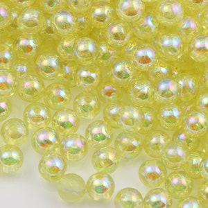 May include: A close-up of a pile of yellow iridescent round beads. The beads are translucent and have a slight shimmer to them.