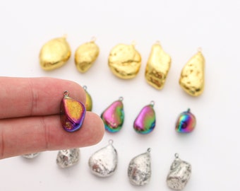 May include: Assortment of iridescent, gold, and silver gemstone pendants. The pendants are shaped like irregular, flat stones with a hole at the top for stringing. The iridescent pendants have a rainbow sheen.