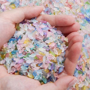 May include: A handful of colorful, translucent leaf-shaped beads in various pastel colors, including pink, blue, yellow, and green. These small beads are ideal for crafting and jewelry making.