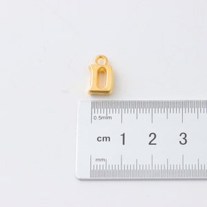 May include: Gold-colored metal letter D charm pendant. The charm is approximately 1 cm in height.