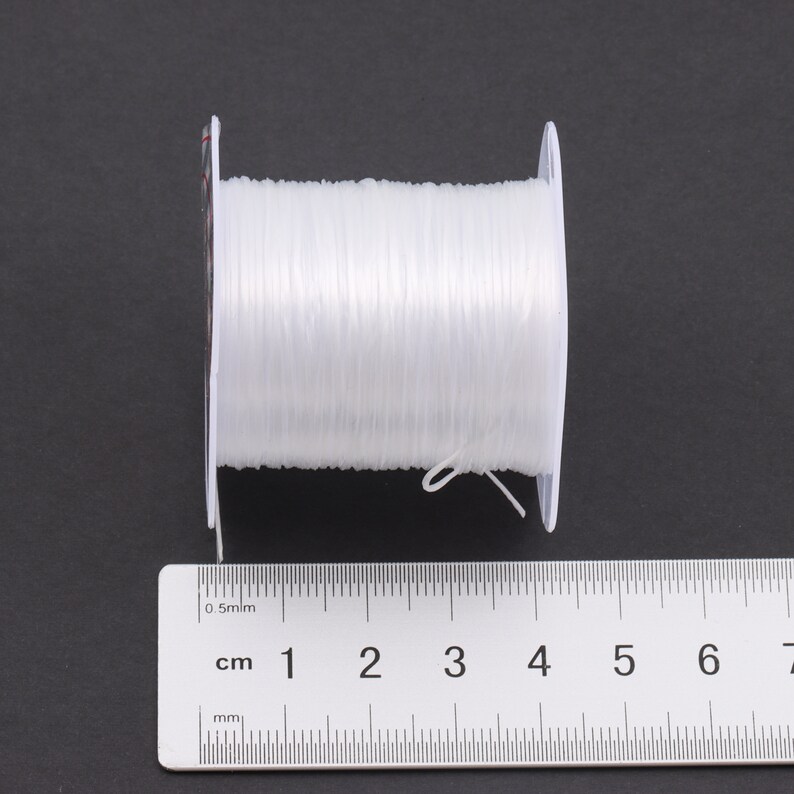Puede incluir: Un carrete de hilo el&aacute;stico transparente, que mide 6 cm de largo, con una etiqueta blanca que dice "0,5 mm".